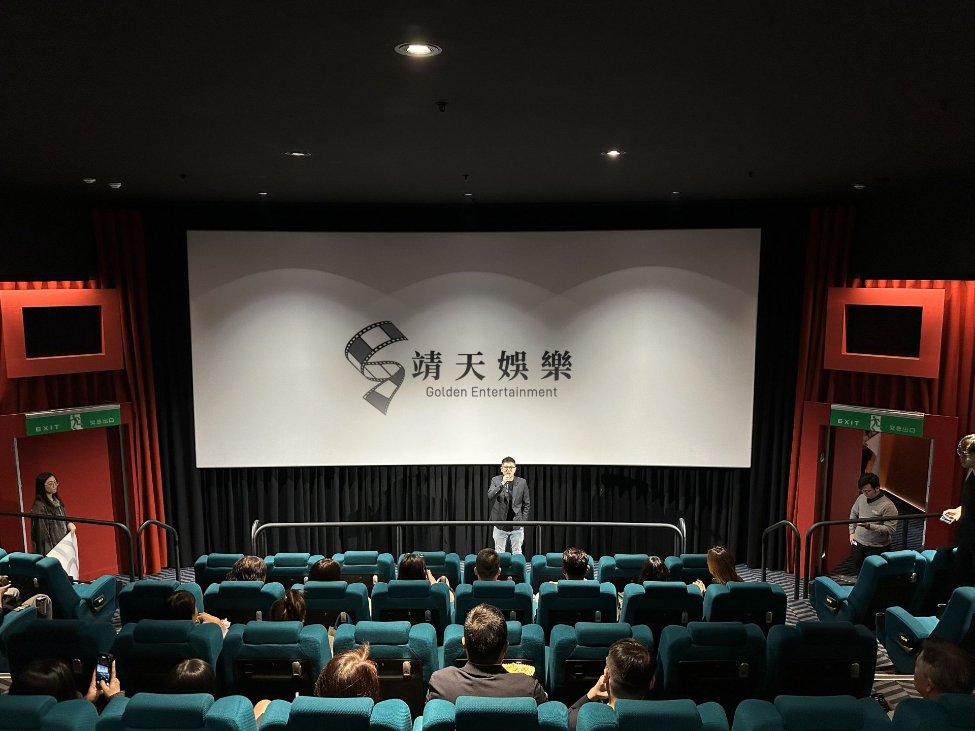 特映會現場,靖天電視台副總經理 陸靖天站在大銀幕前發表致詞,觀眾席坐滿期待觀影的影迷。靖天娛樂/提供