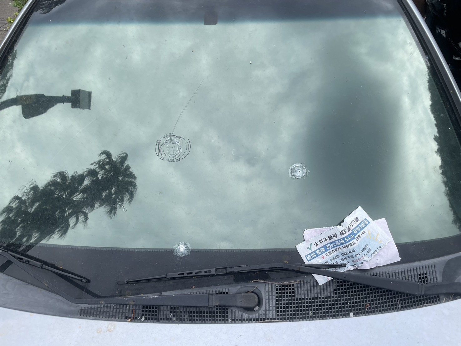 1輛停放在學校附近的銀色轎車，車身和玻璃佈滿了多處彈孔。