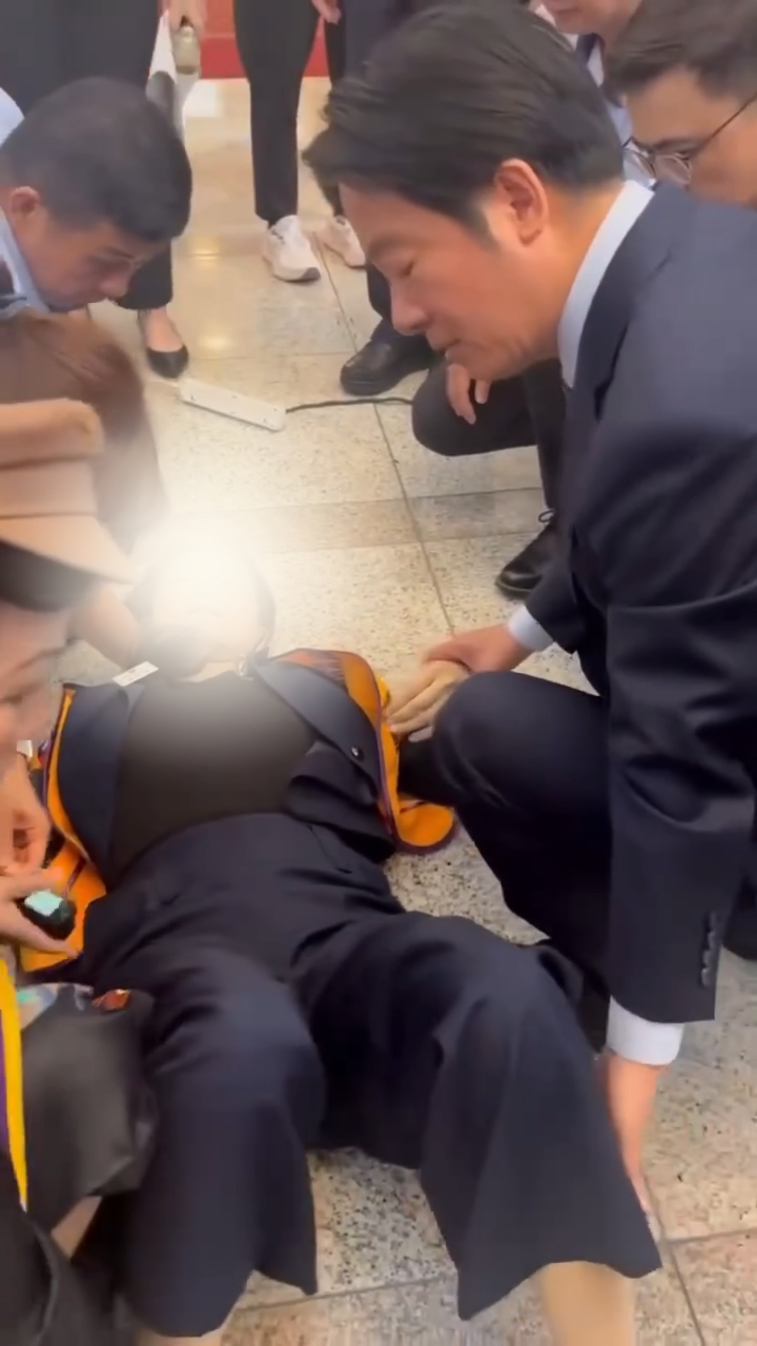 「獅姐」在眾人準備大合照前突然昏倒。賴清德見狀,立刻半跪在地為其進行簡單的診斷和急救。