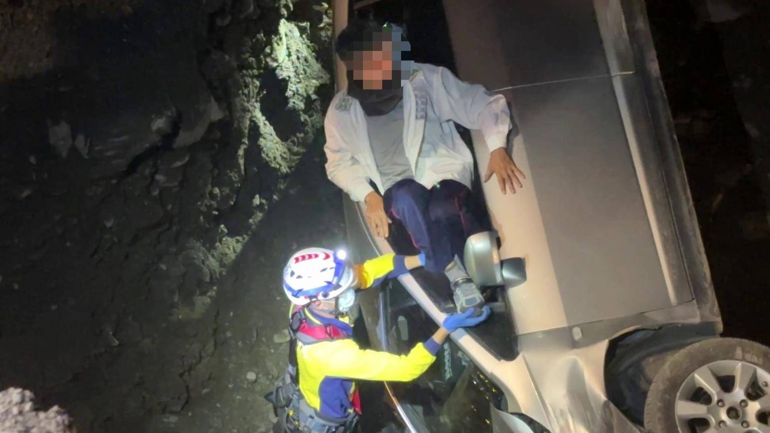 救援人員立即調派器材車，利用機械吊臂將受困於溪床的丈夫及妻子吊掛上岸