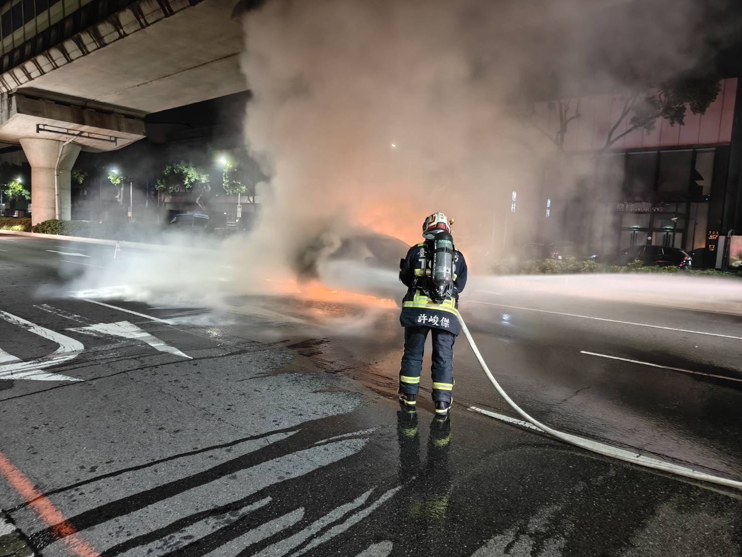 西屯區文心路三段凌晨發生自小客車火警，消防人員迅速佈線出水灌救，現場火勢一度猛烈。（讀者提供／消防局提供）