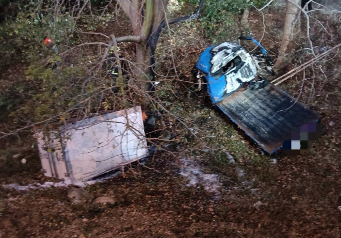 小貨車撞擊出口槽化線橋墩後翻落邊坡並起火燃燒,火勢撲滅後可見車輛殘骸散落林間。